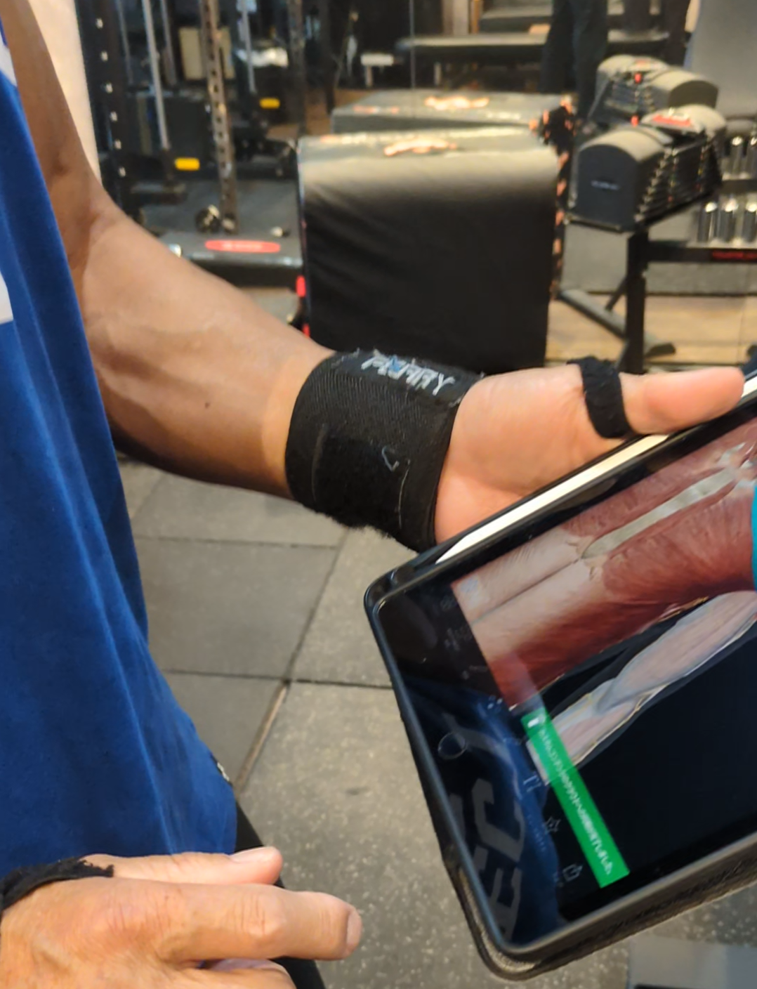 香里園のパーソナルジム BARON で、代表トレーナーがiPadでフォーム指導を行う様子